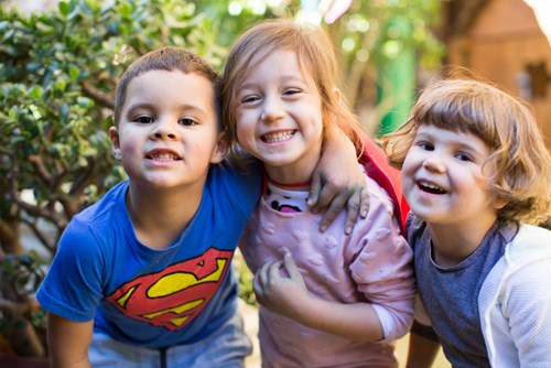 Three children in garden smiling at camera